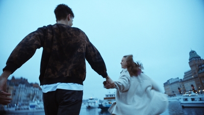 a man and a woman holding hands walking down a street