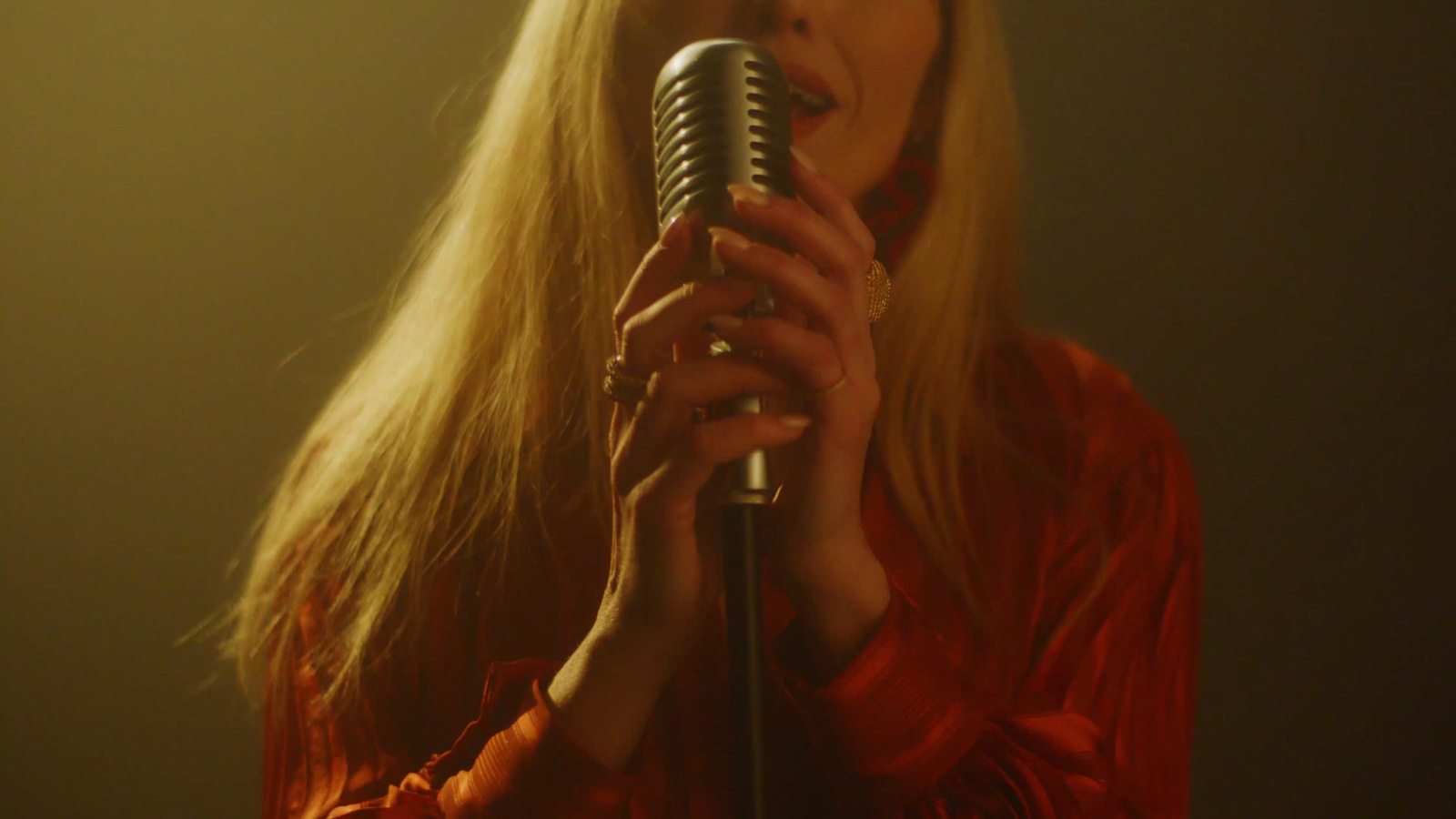 a woman with long blonde hair holding a microphone