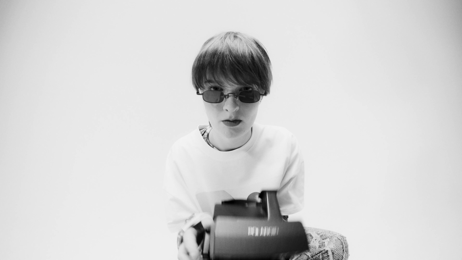 a young boy sitting on the ground holding a camera