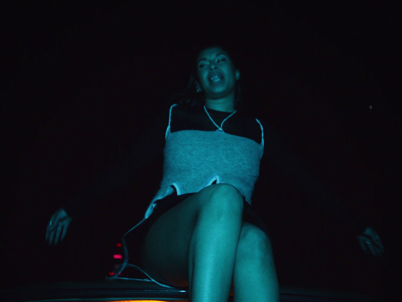 a woman sitting on top of a car in the dark