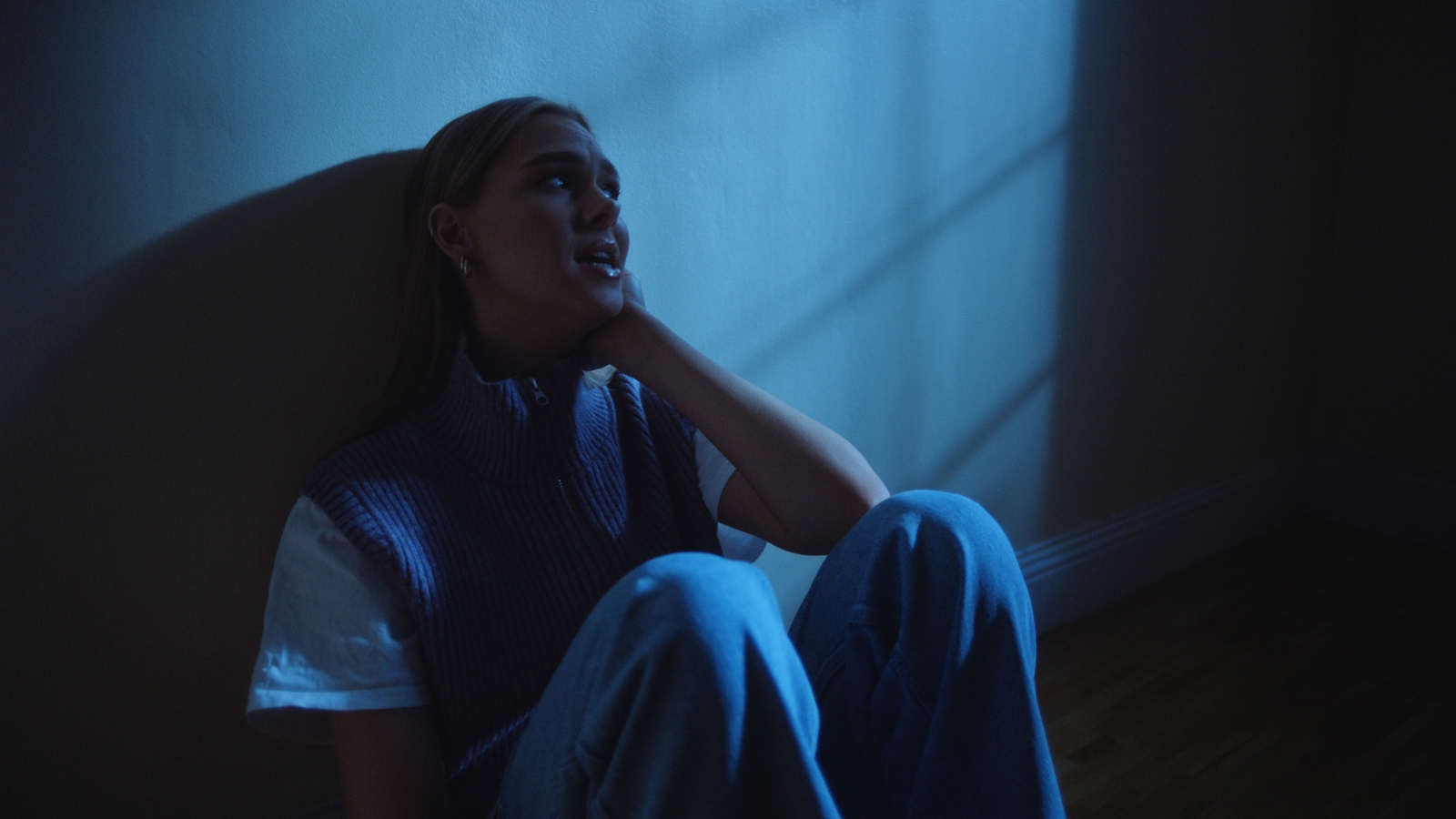 a woman sitting on the floor in a dark room