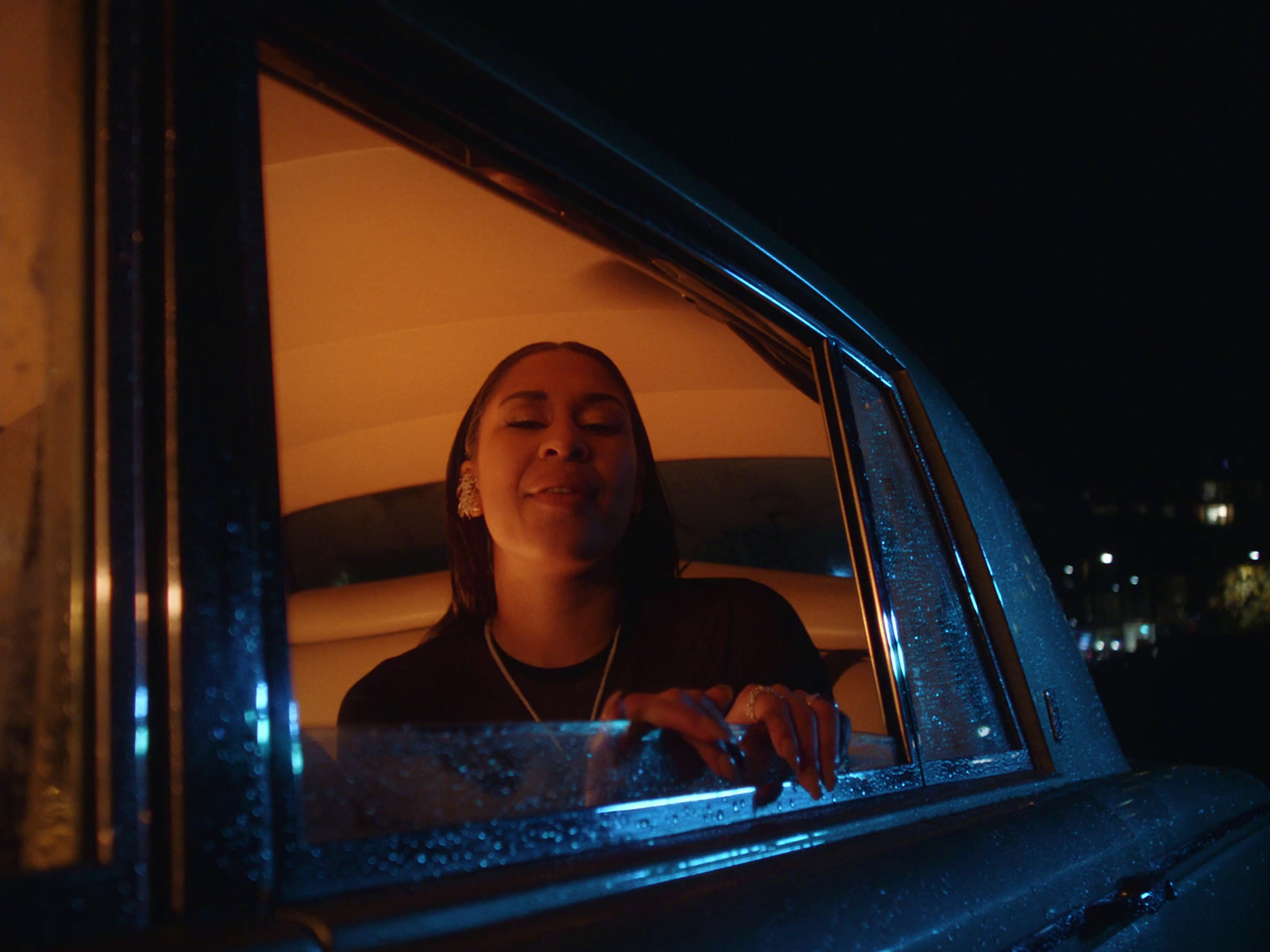 a woman sitting in the back of a car at night