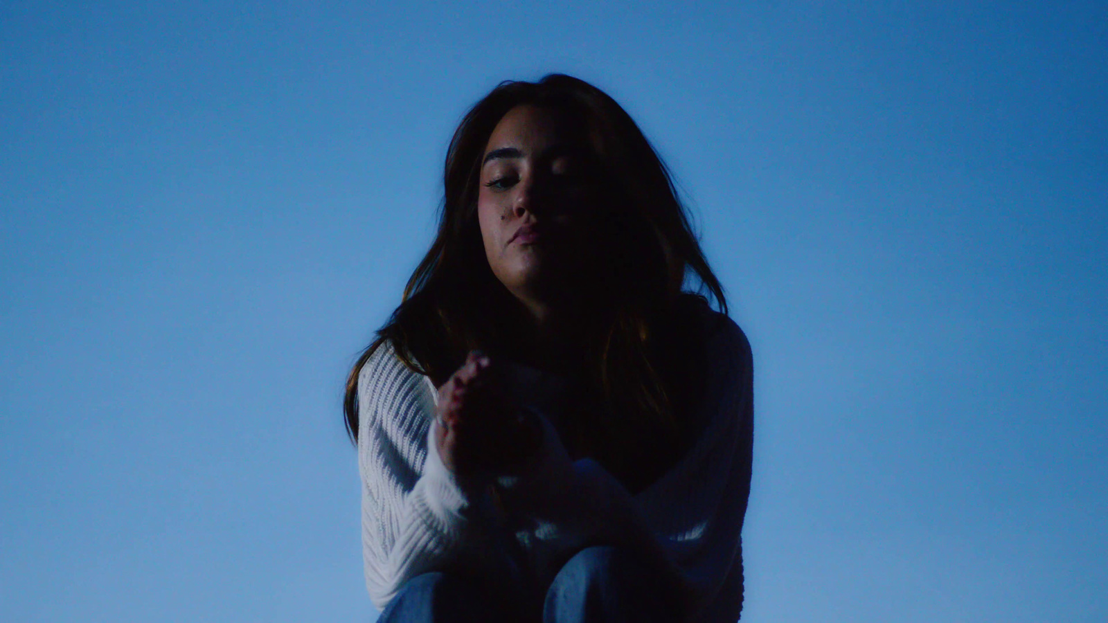 a woman sitting on the ground with her hands together