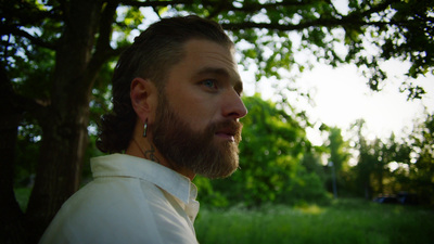 a man with a beard standing in front of a tree