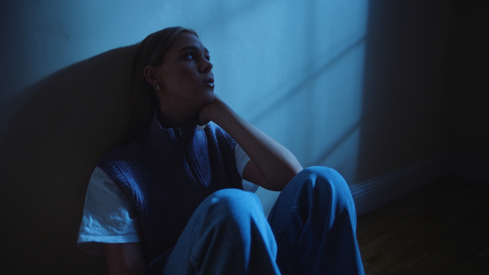 a woman sitting on the floor in a dark room