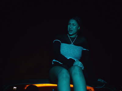 a woman sitting on top of a car in the dark