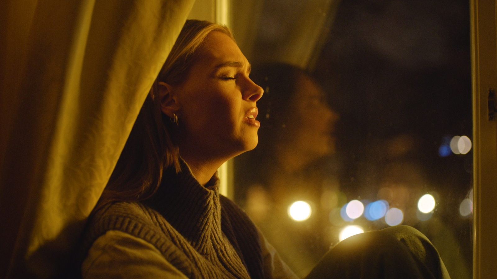 a woman looking out of a window at night