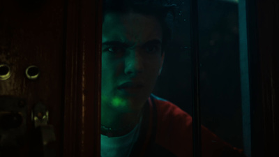 a man in a red jacket looking out of a door