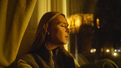 a woman sitting in front of a window with her eyes closed