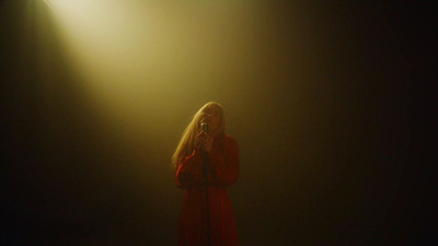 a woman in a red dress standing in front of a light