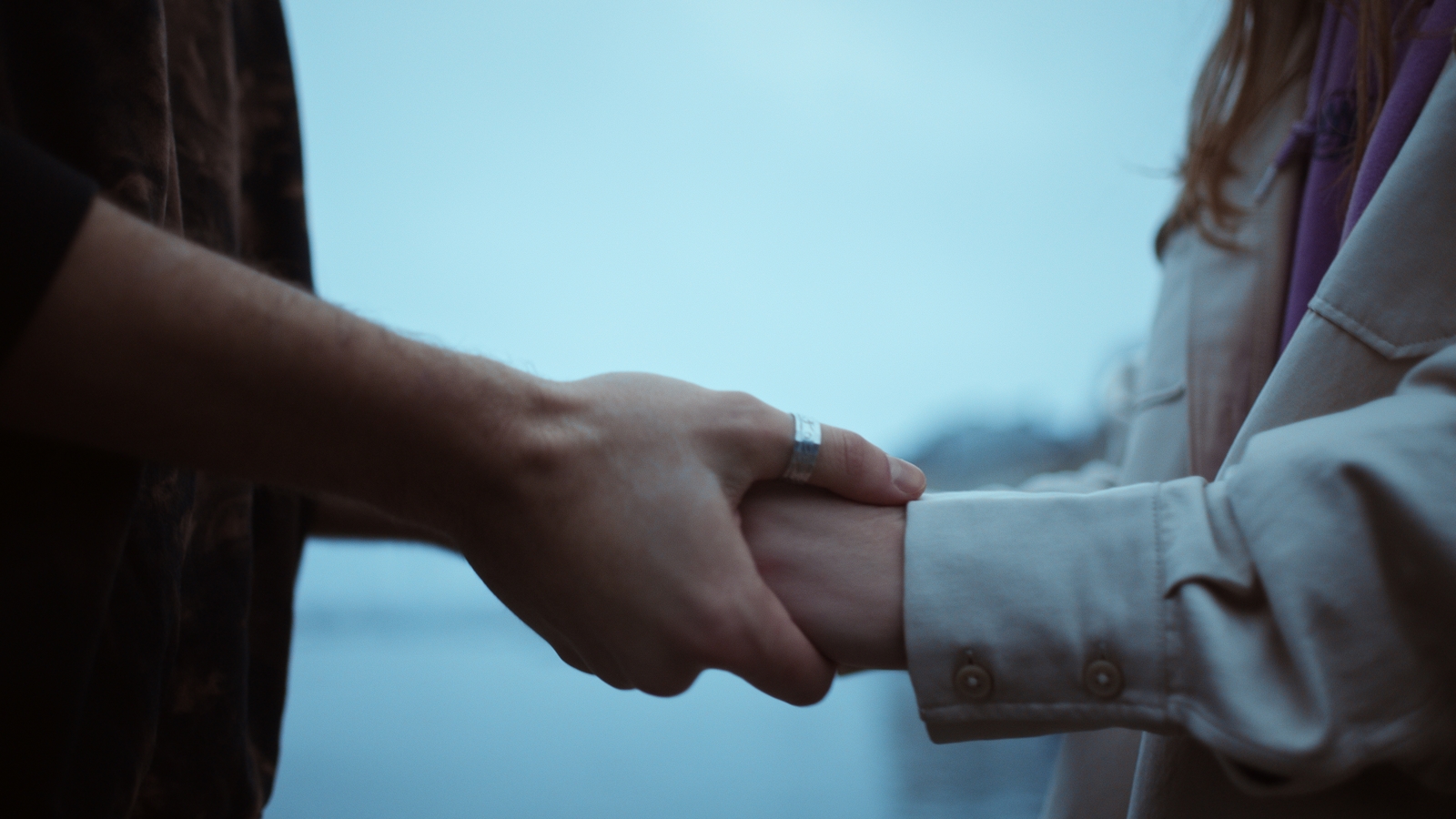 a couple of people holding hands over a body of water