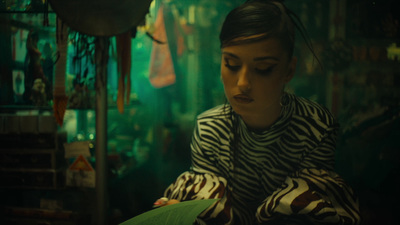 a woman sitting down holding a green umbrella