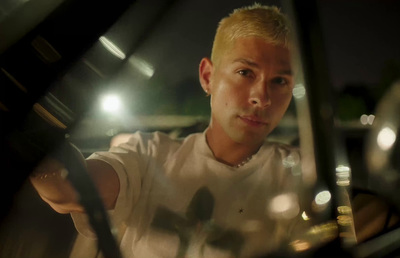 a man in a white shirt driving a car at night