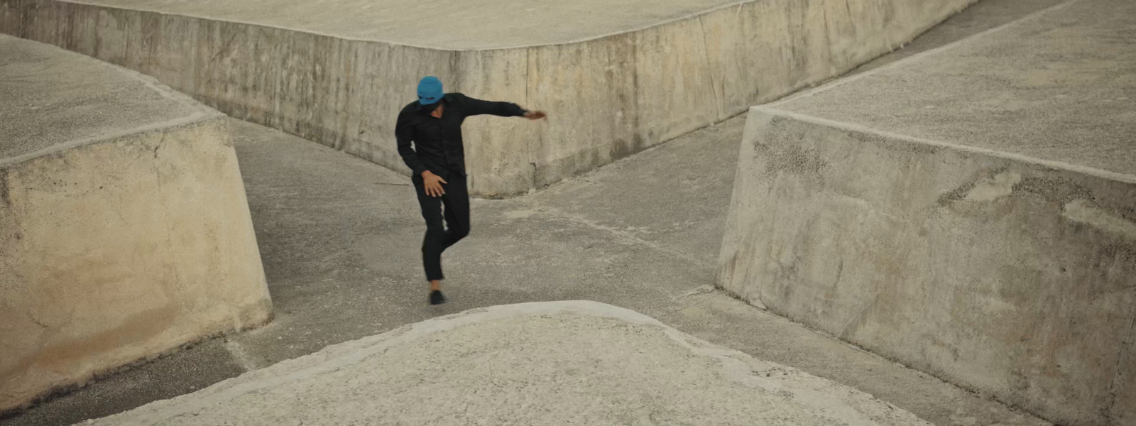 a man in a blue hat is standing in a concrete area