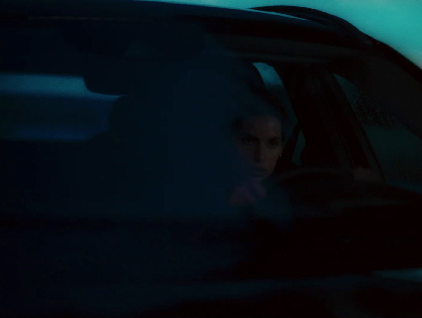 a woman sitting in a car in the dark