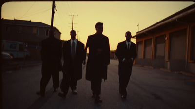 a group of men walking down a street at sunset