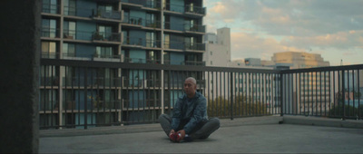 a man sitting on the ground in front of a building