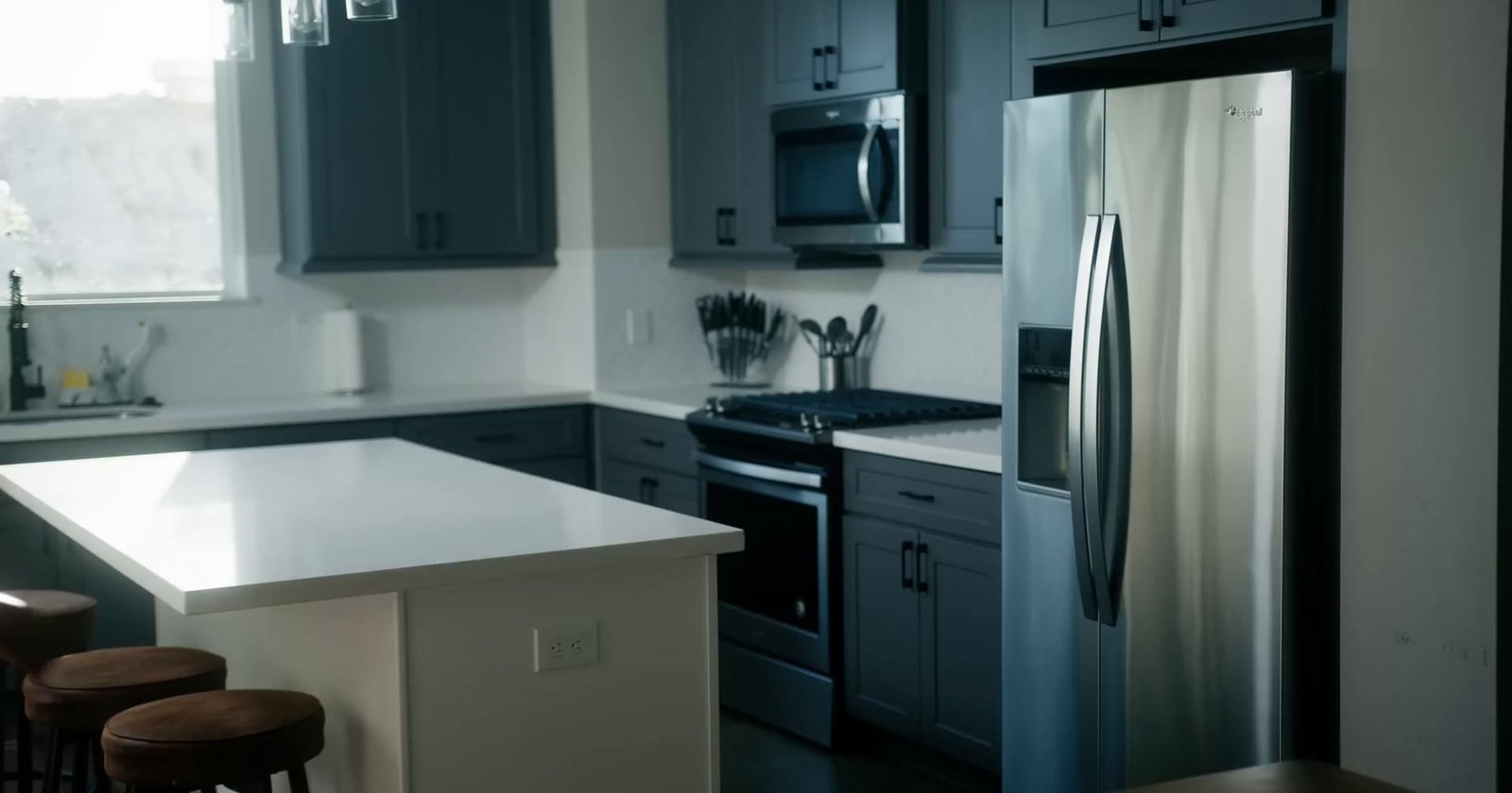 a kitchen with a refrigerator, stove, sink and stools