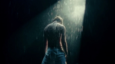 a man standing in the rain with his back to the camera