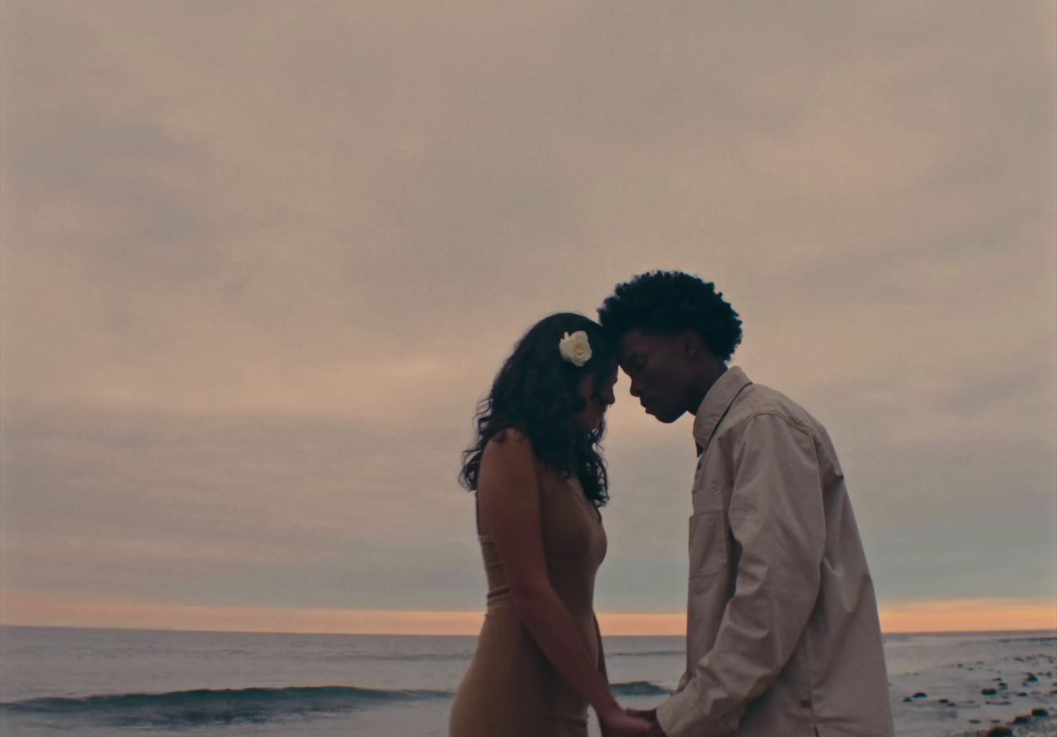 a man and woman standing on a beach next to the ocean