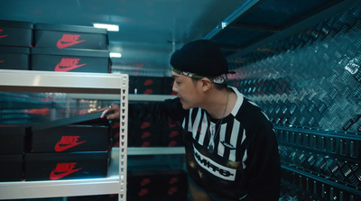 a man in a black and white shirt is looking at a rack of nike shoes