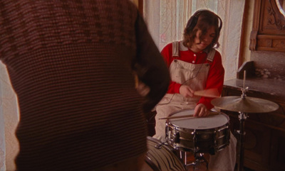 a woman in a red shirt is playing the drums