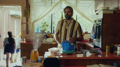 a man standing in a kitchen holding a blue bag