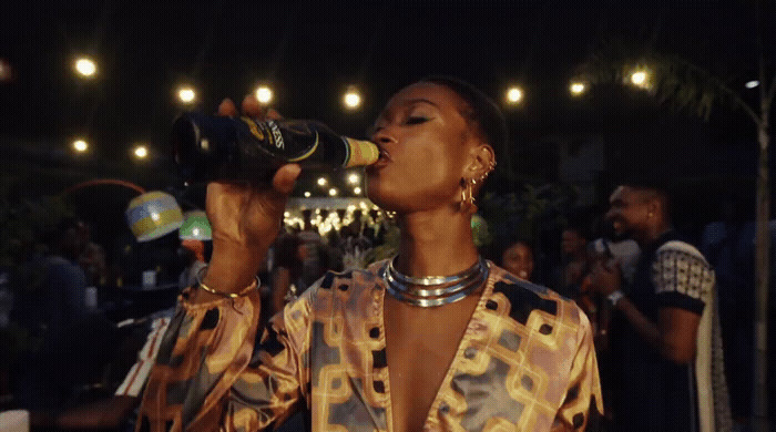 a woman drinking from a bottle while standing in front of a crowd