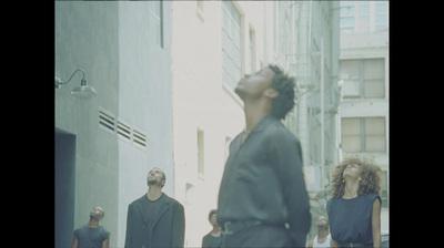 a group of people walking down a street next to tall buildings