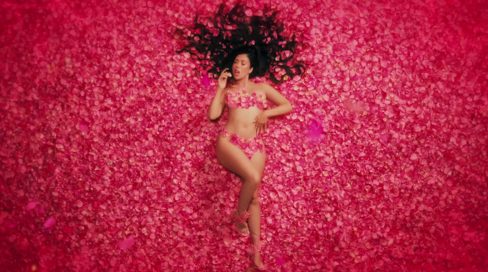 a woman in a pink bikini laying on a bed of flowers