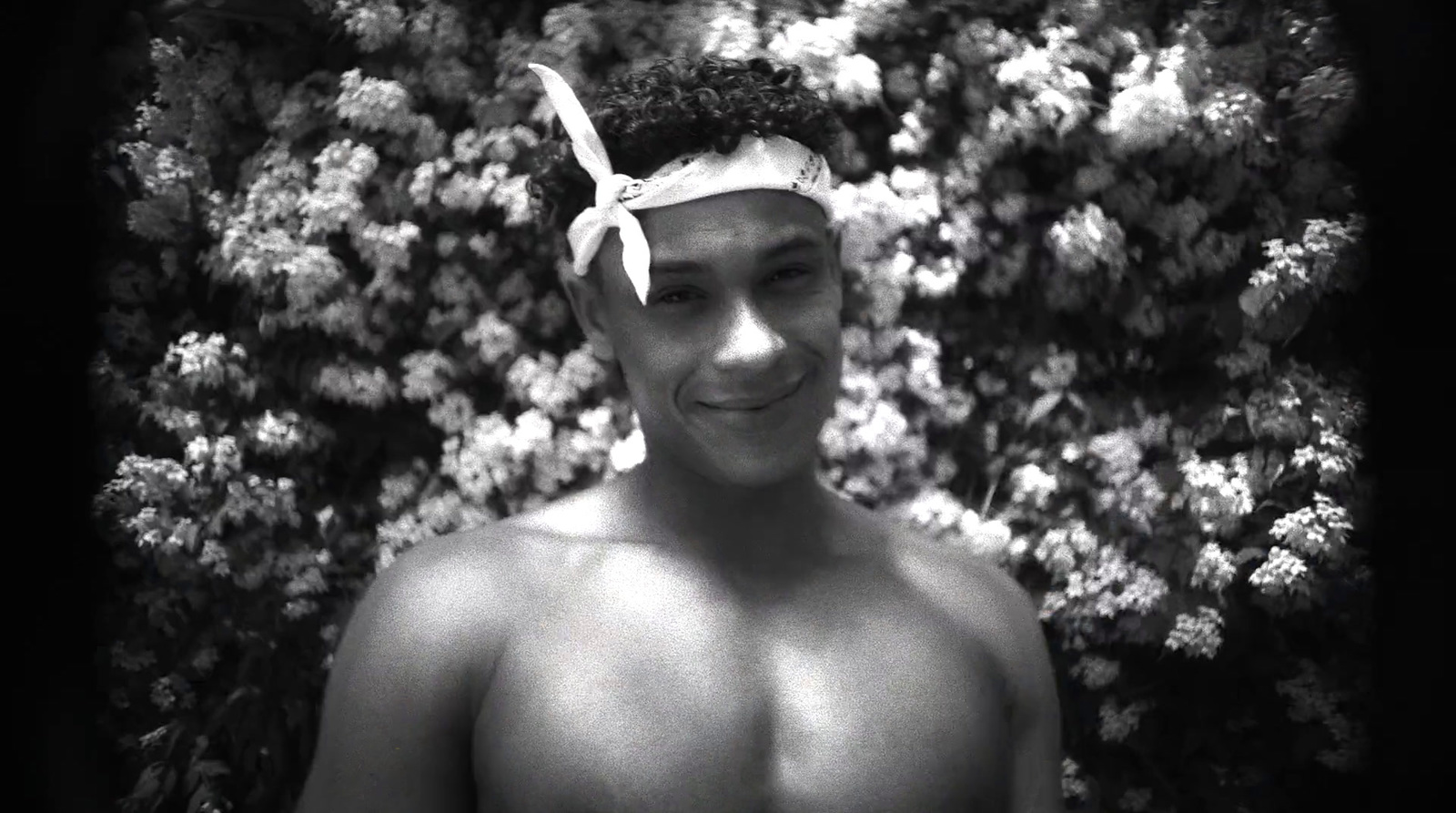 a man with no shirt standing in front of flowers