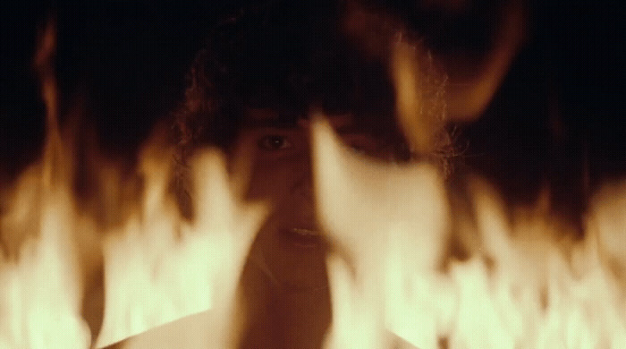 a woman talking on a cell phone in front of a fire