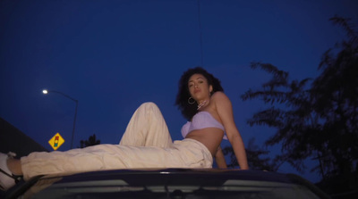 a woman in a bikini laying on top of a car