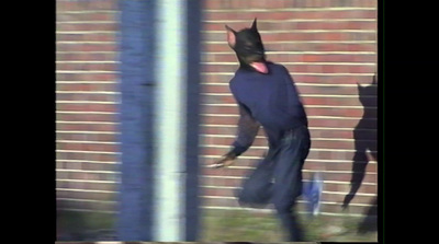 a man in a cat costume walking past a brick wall