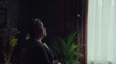 a woman standing in front of a window next to a potted plant