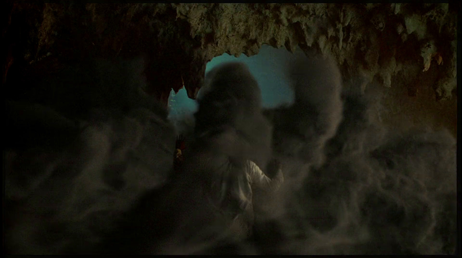 a man standing in a cave with smoke coming out of it