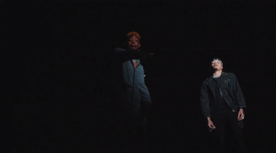 two men standing in the dark with one pointing at the other