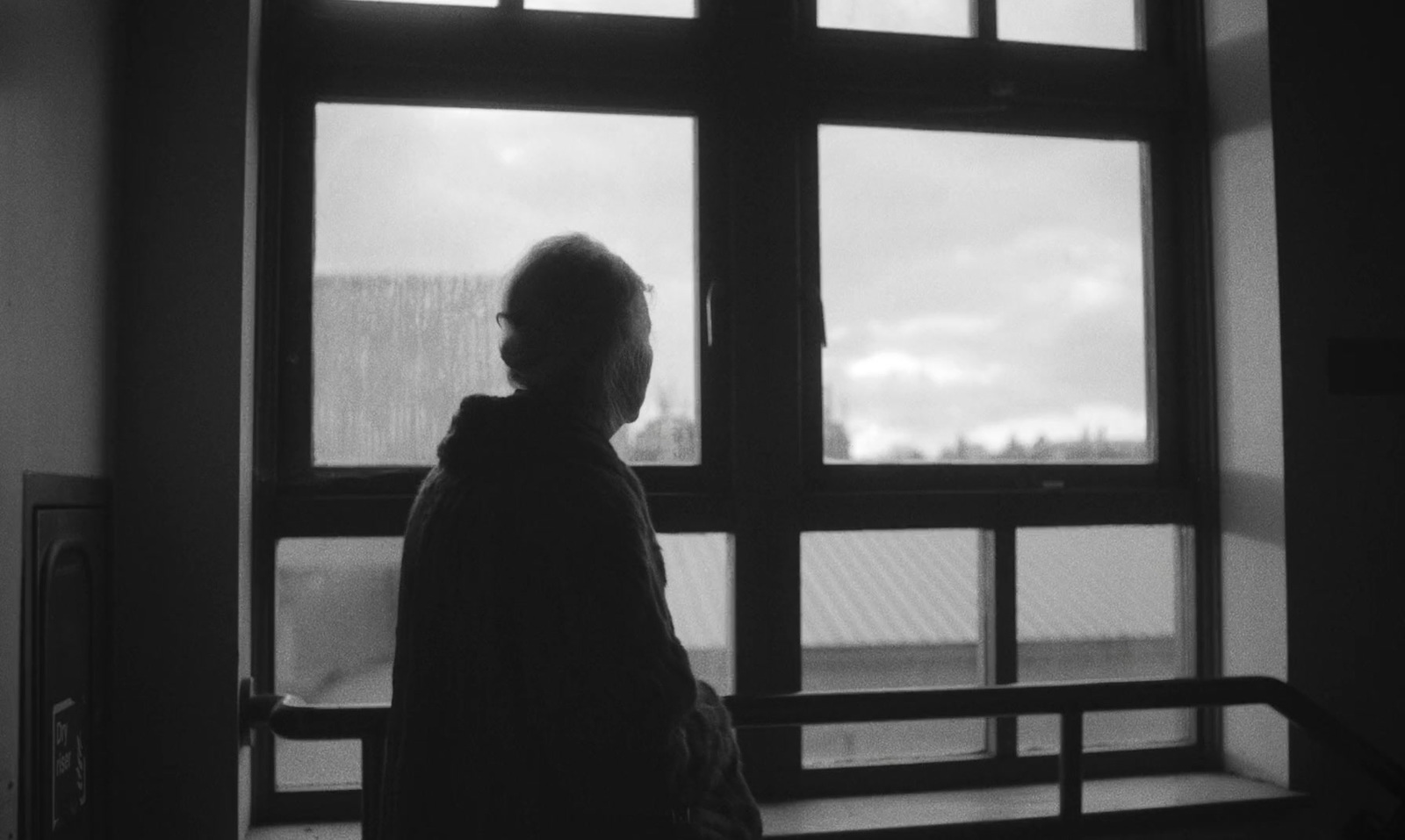 a black and white photo of a person looking out a window