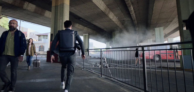 a couple of men walking down a street next to a bridge