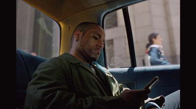 a man sitting in the back seat of a car using a cell phone