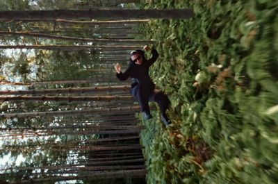 a man walking across a bridge made of trees