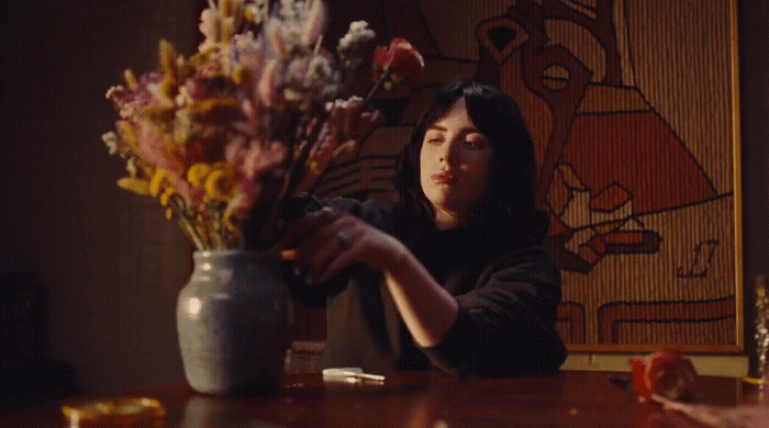 a woman sitting at a table with a vase of flowers