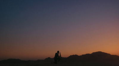 a man standing in the middle of a desert at sunset