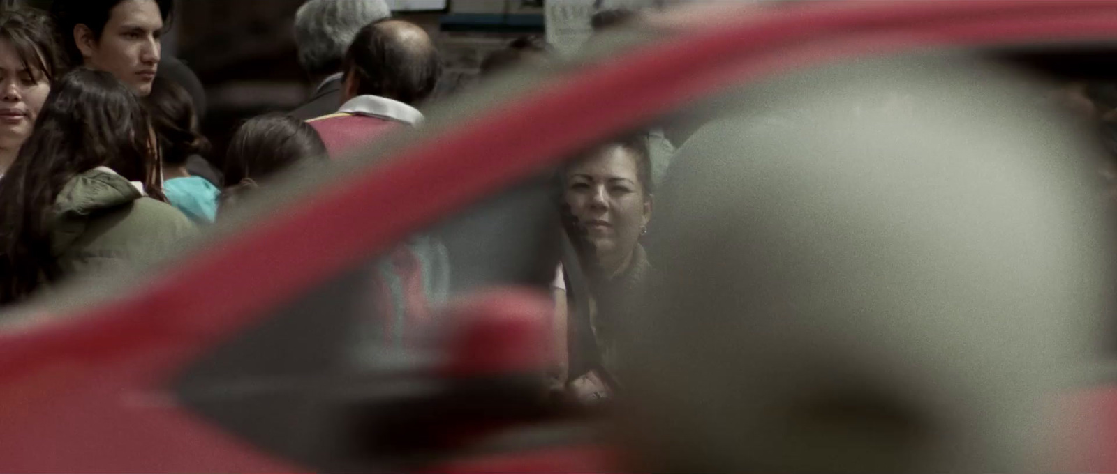 a group of people standing around a red car