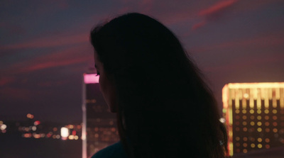 a woman standing in front of a city skyline at night