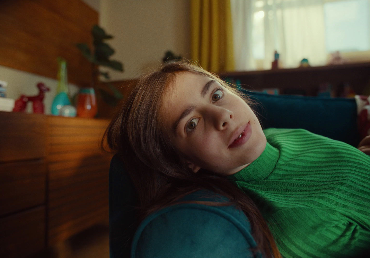 a woman sitting on a couch looking up at the camera