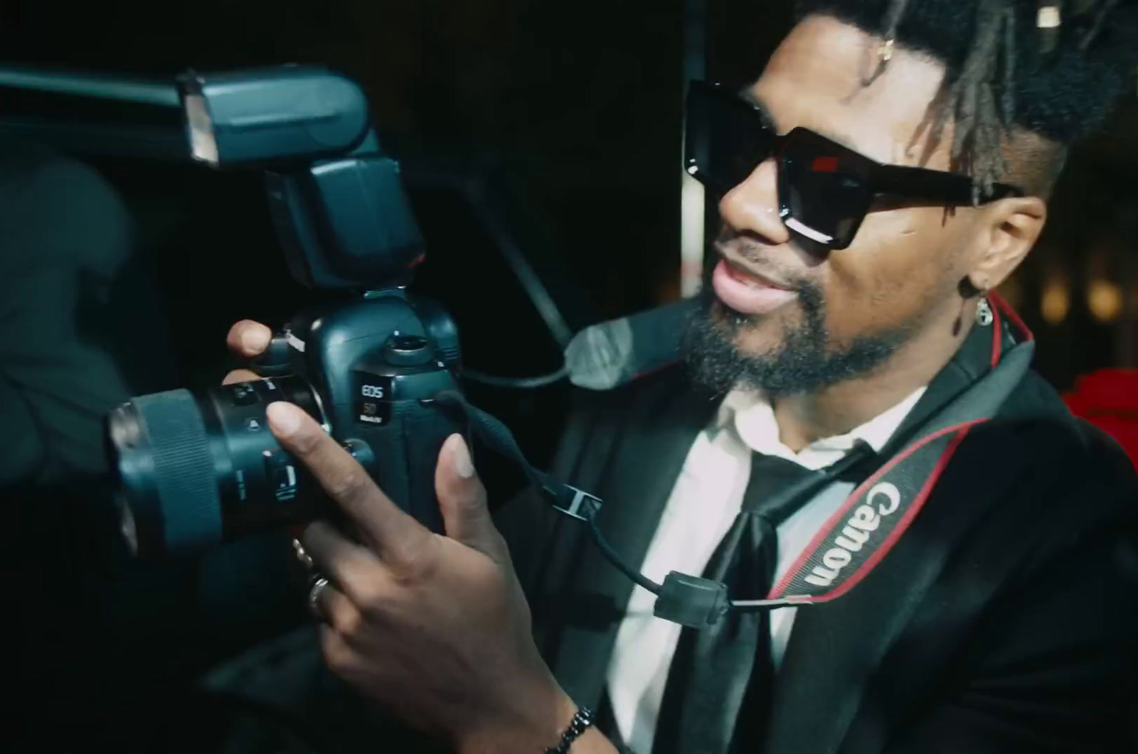 a man in a suit and sunglasses holding a camera