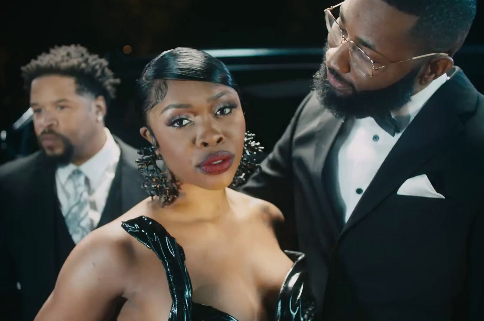 a woman in a black dress standing next to a man in a tuxedo