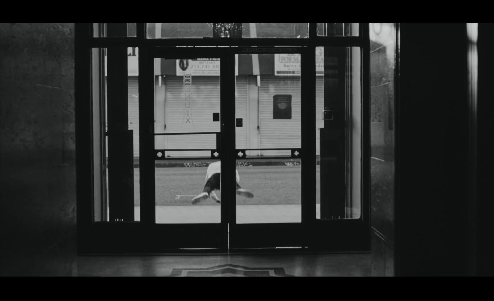 a black and white photo of a person walking out of a building