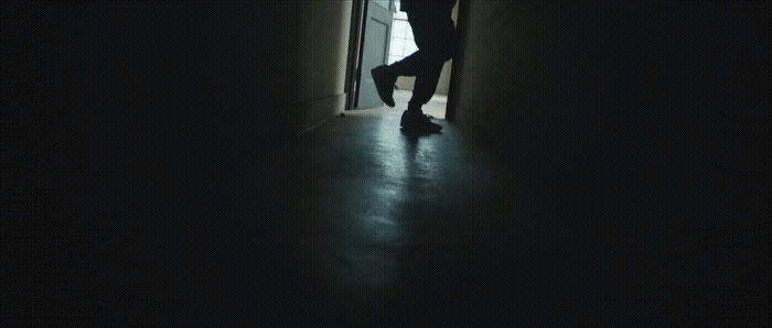 a person standing in a dark hallway with their feet up